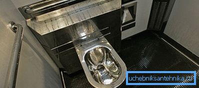 On the photo is a metal sanitary fixture located in the train carriage. On the photo is a metal sanitary fixture located in the train carriage.
