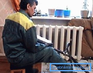 In the photo, the plumber is washing the radiators in the apartment In the photo, the plumber is washing the radiators in the apartment