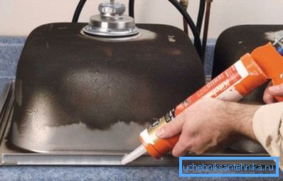 Applying silicone to the inside of a stainless steel kitchen sink before installing it in the worktop